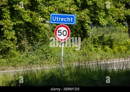 Panneau d'entrée pour Utrecht, pays-Bas, avec un panneau de limitation de vitesse de 50 km h sur une route de campagne, entouré de verdure par une journée ensoleillée. Banque D'Images