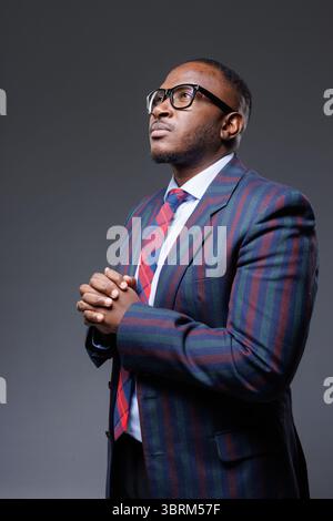 Homme d'affaires africain confiant en costume et lunettes, leader moderne avec ambition et vision, montrant l'élégance professionnelle et la concentration Banque D'Images