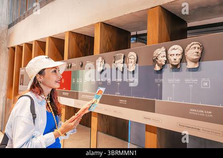 5 mai 2025, Canakkale, Turkiye : jeune femme engagée dans la lecture de l'histoire de l'Empire romain tout en explorant une exposition de musée attrayante Banque D'Images