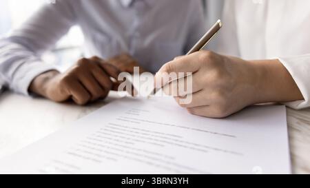 Gros plan de la main féminine tenant le stylo et signant le contrat Banque D'Images