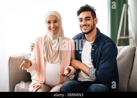 Portrait d'un couple musulman joyeux qui attend bébé posant à la maison Banque D'Images