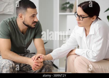 Soldat homme avec TSPT et psychologue tenant la main au bureau Banque D'Images