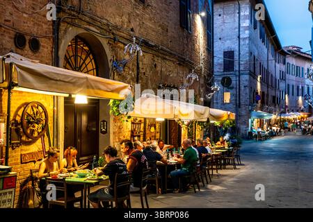 Les gens assis à l'extérieur D'Un restaurant mangeant le dîner dans la ville de Sienne, Toscane, Italie. Banque D'Images