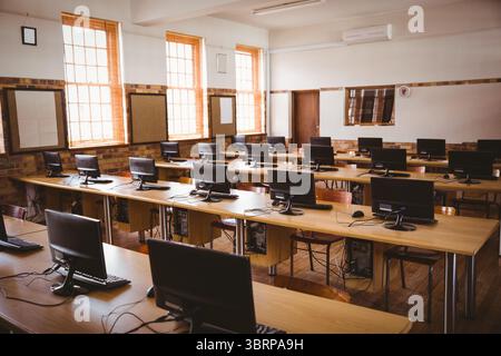 La salle de classe informatique de conception plate montre des bureaux en bois avec des moniteurs, des claviers et des fenêtres à guillotine Banque D'Images