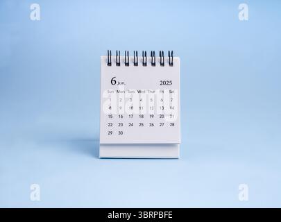 Un calendrier de bureau de juin 2025 pour l'organisateur à planifier et rappeler debout, isolé sur fond horizontal bleu, minimaliste. Petit calendrier de table blanc Banque D'Images