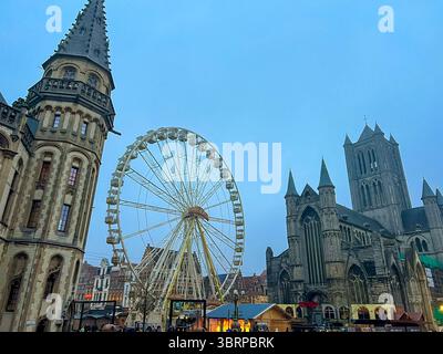 Grande roue festive derrière la cathédrale de Gand avec la lueur du marché de noël Banque D'Images