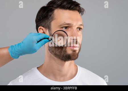 Médecin main Vérification de la peau du visage de l'homme avec le Dermatoscope Banque D'Images