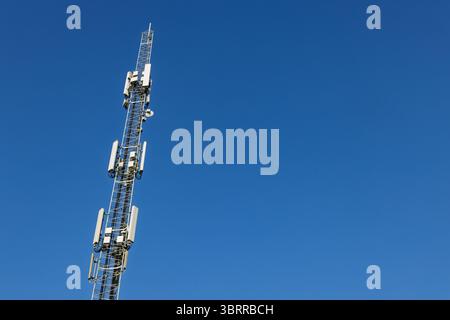 Gros plan des antennes blanches sur la tour cellulaire. Tour de transmission de données mobiles avec antennes contre un ciel bleu clair, concept d'équipement de télécommunications, Banque D'Images