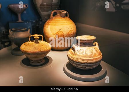 5 mai 2025, Canakkale, Turkiye : d'anciens pots et cruches en argile avec des décorations sont exposés sur des stands illuminés dans un musée Banque D'Images