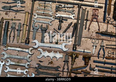 Divers outils anciens accrochés sur une planche de bois, créant un fond vintage et rustique parfait pour l'artisanat et les concepts de réparation Banque D'Images