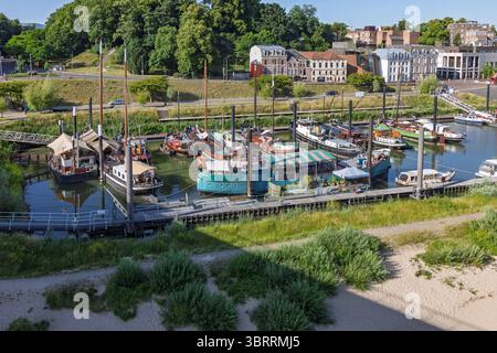 Une vue panoramique sur une marina animée 'Lindenberghaven' remplie de divers bateaux et péniches amarrées le long de jetées en bois, avec des bâtiments et un vert luxuriant Banque D'Images