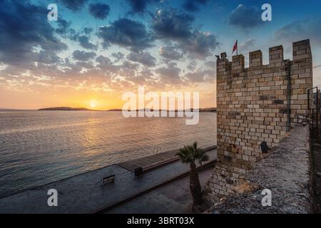 Drapeau turc agitant au-dessus du château de Foca au coucher du soleil avec un ciel nuageux spectaculaire, situé dans la province d'Izmir, Turquie Banque D'Images