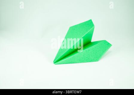 Avion de papier ondulé vert sur un fond blanc, isolé. Concept (idée) de compagnies aériennes, liberté, leadership, écologie, succès, et la durabilité Banque D'Images