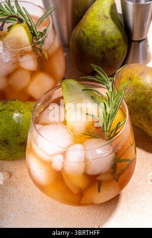 Boisson fruitée à l'alcool, cocktail doux de poire froide avec rhum, liqueur, anis et brin de romarin, garni de poire en tranches Banque D'Images