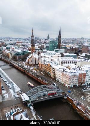 Vue aérienne du paysage urbain enneigé, capturant la flèche de Nikolaikirche et le pont sur le canal, une scène hivernale de tranquillité urbaine, Hambourg, Hambourg, Allemagne. Banque D'Images