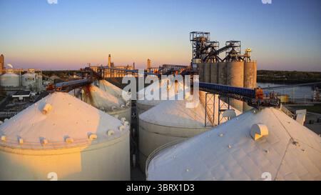Vue aérienne des silos imposants et de l'architecture industrielle rencontrent la lumière de l'heure d'or, projetant de longues ombres à travers le paysage, Toledo, Ohio, États-Unis. Banque D'Images