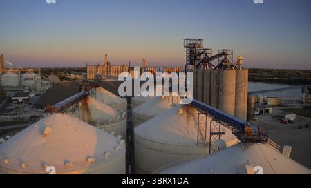 Vue aérienne de silos embrassés par le soleil projetant de longues ombres alors que la rivière Maumee scintille au loin, Toledo, Ohio, États-Unis. Banque D'Images