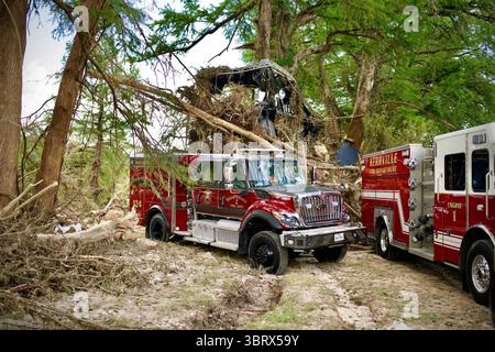 Les camions de pompiers du comté de Bexar et du service d'incendie de Kerrville répondent aux zones endommagées par les inondations à Kerrville, Texas, le 11 juillet 2025. Des débris et des véhicules endommagés sont vus logés dans les arbres à la suite de graves inondations. Image reproduite avec l'aimable autorisation de la Maison Blanche. Banque D'Images