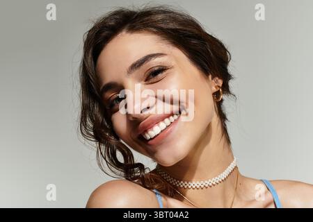Jeune femme au beau maquillage affiche son sourire radieux dans un cadre de studio. Banque D'Images