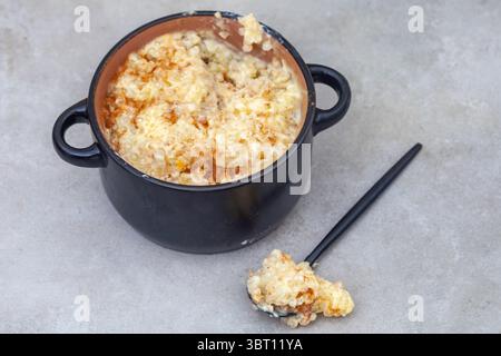 Délicieux et réconfortant Tapioca puddi8ng dans un bol en forme de pot sur un fond gris avec une cuillerée de pudding à côté Banque D'Images