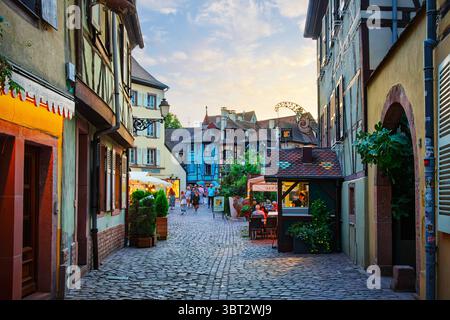 Vue crépusculaire sur les bâtiments à colombages et les cafés illuminés dans le quartier médiéval historique de la petite Venise de Colmar, en France. Banque D'Images