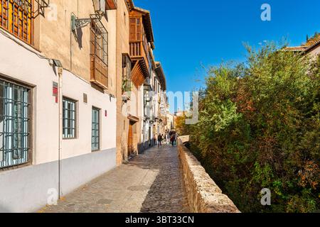 L'étroite rue médiévale Carerra del Darro longeant la rivière Darro dans le centre historique de la ville andalouse de Grenade, en Espagne. Banque D'Images