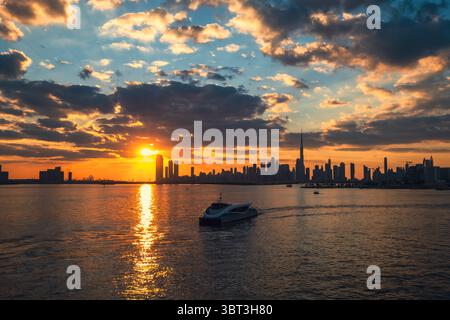 Coucher de soleil épique sur fond d'horizon de la ville, avec un bateau au premier plan et une silhouette de la ville sur un ciel coloré rempli de nuages, blen Banque D'Images