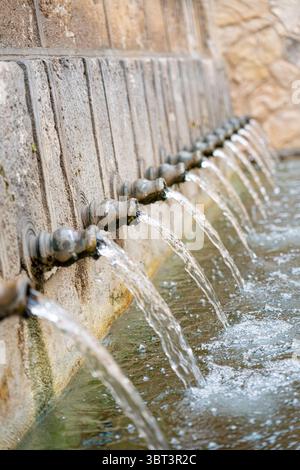 Cascades d'eau de plusieurs becs de pierre dans une piscine tranquille à Brihuega, Guadalajara, capturant l'essence de l'architecture espagnole traditionnelle et Banque D'Images