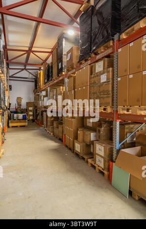 Les boîtes en carton empilées sur des palettes en bois remplissent l'espace de stockage de l'entrepôt, représentant la logistique, la distribution et la gestion des stocks Banque D'Images
