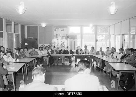 Groupe de joueurs de football Telstar écoute le discours de l'entraîneur., Whizgle News, Dutch Desk, pays-Bas, 1950 - 2000. Ces rubriques sont illustrées dans l'image. La scène se déroule dans une pièce spacieuse avec de grandes fenêtres permettant à la lumière naturelle de s'inonder, créant une atmosphère lumineuse et accueillante. Les murs sont ornés de panneaux de couleur claire, complétant la luminosité globale du cadre. Au centre de la pièce, une longue table rectangulaire est disposée, entourée d'un groupe de personnes engagées dans la discussion. Les participants, principalement des hommes, sont habillés en costumes, affichant une gamme de couleurs de Banque D'Images