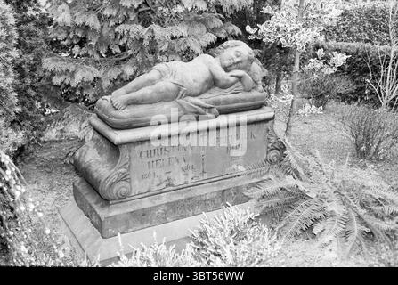 Cimetière Kleverlaan Haarlem Kleverlaan pays-Bas, Whizgle News, Dutch Desk, pays-Bas, 1950 - 2000 le 06-02-1995. L'image montre ces rubriques. La scène représente un mémorial solennel niché dans la verdure, avec une figure angélique magnifiquement sculptée d'un enfant endormi positionné au sommet d'un monument en pierre. Les traits délicats de l'enfant sont accentués par des détails complexes dans la sculpture, véhiculant un sentiment de paix et de tranquillité. La statue se trouve sur le côté, dégageant une aura sereine. Autour du monument se trouvent des fougères vertes luxuriantes et d'autres feuillages, qui fournissent un na Banque D'Images