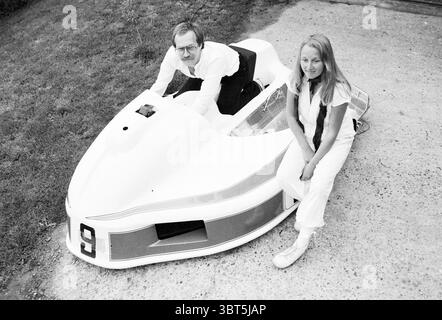 COR et Carla v. Reewijk on sidecar race Motorcycles course Motorcycles, Whizgle News, Dutch Desk, pays-Bas, 1950 - 2000 on 21-05-1981. Ces rubriques sont illustrées dans l'image. La scène présente un cadre extérieur unique avec un véhicule élégant et de style rétro ressemblant à un karting ou un bateau de course. Le véhicule, principalement blanc avec des accents rouges audacieux, est profilé et accrocheur, évoquant un sentiment d'aventure et de nostalgie. Au premier plan, un homme se penche sur l'avant du véhicule, portant des lunettes et une chemise blanche jumelée à un pantalon sombre. Son expression transmet un mélange de concentration Banque D'Images