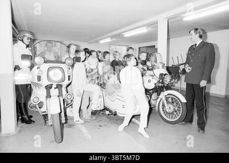 Tour Traffic police Haarlem police Haarlem pays-Bas, Whizgle News, Dutch Desk, pays-Bas, 1950 - 2000 on 26-06-1985. Voici les rubriques de l'image. Dans un vaste parking souterrain, un groupe de personnes, principalement des enfants et quelques adultes, se réunit autour de deux motos distinctement conçues. Les motos sont majoritairement blanches, avec des lignes épurées et des side-cars visibles. Le cadre est bien éclairé, avec des lumières fluorescentes brillantes qui projettent une lueur légèrement froide et stérile sur la scène. Les enfants affichent un mélange d'excitation et d'admiration, certains grimpant avec impatience ou posant à côté de t Banque D'Images