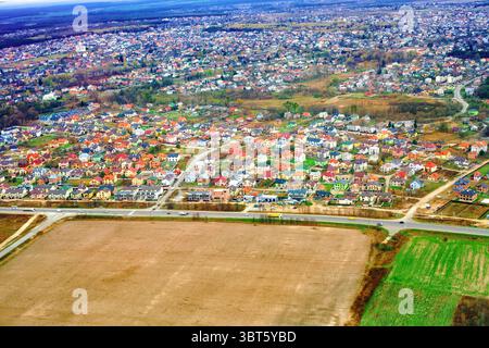 Vue aérienne de l'automne village de Zymna Voda maisons individuelles colorées, routes avec voitures de conduite et champs dans la région de Lviv, Ukraine. Quartier résidentiel Banque D'Images