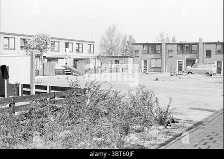 Vue d'ensemble Blaauwplein Parkwijk Pleinen Haarlem Blaauwplein pays-Bas, Whizgle News, Dutch Desk, pays-Bas, 1950 - 2000 sur 07-05-1976. L'image montre ces rubriques. La scène présente une vue monochromatique d'un quartier résidentiel, caractérisé par un aspect minimaliste et un peu dur. D’un côté, un groupe de modestes bâtiments de deux étages forme une toile de fond, leurs façades marquées par de grandes fenêtres et de simples lignes architecturales. Ces structures, qui font probablement partie d'un complexe immobilier, sont disposées de façon linéaire, mettant l'accent sur un sentiment de communauté. Au premier plan, un espace ouvert se déploie, Bor Banque D'Images