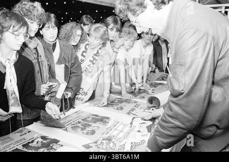 Il suffit de faire le festival Noordwijkerhout festivités et manifestations Noordwijkerhout, Whizgle News, Dutch Desk, pays-Bas, 1950 - 2000 le 01-04-1983. L'image contient ces rubriques. Dans une scène animée remplie d’énergie juvénile, un groupe d’adolescents est réuni autour d’une longue table ornée de diverses affiches et de matériel promotionnel. Les individus, garçons et filles, présentent un mélange de styles reflétant les modes de leur époque - certaines tenues de sport décontractées tandis que d'autres portent des t-shirts de groupe et des accessoires qui font allusion à leurs intérêts musicaux. La table est encombrée de vibran Banque D'Images