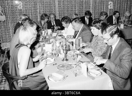 Anniversary Mr. A Bokhorst Equipment Department Spaarndam Stevin Group, Whizgle News, Dutch Desk, pays-Bas, 1950 - 2000 le 29-09-1978. Ces rubriques sont illustrées dans l'image. La scène représente un grand rassemblement autour d'une longue table à manger, où plusieurs groupes d'individus élégamment habillés sont engagés dans un repas. La table est ornée de nappes blanches et de décors soigneusement agencés, avec de l'argenterie brillante et de la verrerie élégante, reflétant le doux éclairage ambiant au-dessus de vous. Le cadre offre une atmosphère chaleureuse et intime, suggérant une occasion formelle ou festive. Les invités, a Banque D'Images