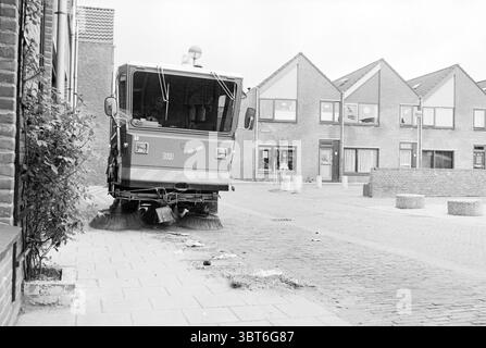Nettoyage 'Clean Ship in the Rose' Rozenprieel Haarlem pays-Bas, Whizgle News, Dutch Desk, pays-Bas, 1950 - 2000 on 21-04-1980. Voici les rubriques de l'image. La scène montre une rue nettoyée par un véhicule compact qui balaye les rues. Le camion, bien positionné au premier plan, est peint dans des tons de gris avec des rayures orange vif et blanc, soulignant son utilité. Il a de grandes brosses arrondies à l'avant qui sont actuellement en contact avec la chaussée, travaillant à éliminer les débris. De chaque côté du véhicule, la rue est entrecoupée de pavés Banque D'Images