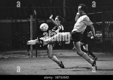 Haarlem - Veendam, Whizgle News, Dutch Desk, pays-Bas, 1950 - 2000 le 25-09-1992. Ces rubriques apparaissent dans l'image. La scène capture un moment intense lors d'un match de football nocturne. Deux joueurs dominent la composition : l'un est à mi-coup, avec une position basse et forte, montrant la détermination et la concentration. Leur posture transmet l'urgence, et leur athlétisme est évident dans les muscles tendus et l'urgence du mouvement. Le deuxième joueur, légèrement derrière, semble se disputer le ballon, avec une expression tout aussi engagée et des membres tendus. En arrière-plan, les contours flous Banque D'Images