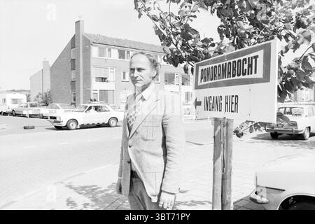 Homme au panneau indiquant l'entrée du virage panoramique du circuit de Zandvoort, Whizgle News, Dutch Desk, pays-Bas, 1950 - 2000 en 1978. Ces rubriques apparaissent dans l'image. Dans un cadre urbain animé, un homme se tient bien en vue au premier plan, dégageant un air de confiance. Il est bien habillé dans un costume de couleur claire, complété par une cravate à motifs qui ajoute une touche de personnalité à sa tenue. Son expression est focalisée, suggérant qu'il est profondément dans la pensée ou engagé dans un but particulier. La toile de fond présente une série de bâtiments résidentiels, caractérisés par un archit simple et moderne Banque D'Images
