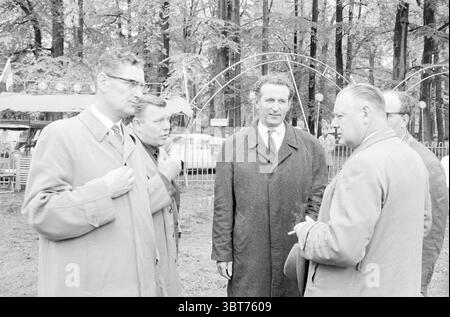 Signaler Cirque Toni Boltini peut-être en raison d'une inspection par la municipalité ou quelque chose de similaire.., Whizgle News, Dutch Desk, pays-Bas, 1950 - 2000. Voici les rubriques de l'image. Un groupe d'hommes se dresse au milieu d'une zone boisée, entourée de grands arbres qui créent une toile de fond sereine. La scène est capturée dans un ton monochrome, améliorant la sensation vintage du moment. Chaque homme porte un manteau, suggérant une journée fraîche, et leurs expressions vont de la discussion engagée à la contemplation réfléchie. Le premier plan présente quatre personnes engagées dans la conversation, dont deux sli Banque D'Images