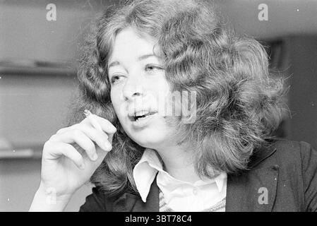 Accueil conseils boutique magasins et kiosques, Whizgle News, Dutch Desk, pays-Bas, 1950 - 2000 sur 05-09-1972. Voici les rubriques de l'image. La scène capture une femme aux cheveux bouclés volumineux qui encadre son visage de manière vivante. Elle semble être en pleine conversation, son expression réfléchie et engagée. Les contours de son visage suggèrent un air d'introspection, et elle tient délicatement une cigarette entre ses doigts, dégageant une aura de sophistication décontractée. Elle est habillée d'un blazer foncé sur une chemise à col clair, ce qui ajoute une touche de contraste à son apparence générale. T Banque D'Images