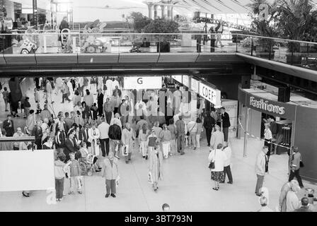 Journée environnementale au terminal de West Schiphol Schiphol, Whizgle News, Dutch Desk, pays-Bas, 1950 - 2000 le 14-05-1993. Ce sont les éléments de l'image. La scène est animée d'activités, mettant en valeur un grand espace ouvert typique d'un centre commercial ou d'un atrium. L'architecture est moderne, avec de hauts plafonds soutenus par des poutres métalliques élégantes qui ajoutent à la sensation d'espace. La lumière naturelle pénètre à partir de grands panneaux de verre au-dessus de la tête, créant des reflets lumineux et des ombres douces sur le sol poli. La foule est diversifiée, mettant en vedette de nombreuses personnes marchant dans diverses directions, certains engagés dans le con Banque D'Images
