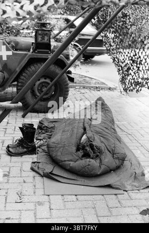 Exercice de l'armée Atlantic Lion Allemagne Armée, Whizgle News, Dutch Desk, pays-Bas, 1950 - 2000 le 20-09-1983. L'image montre ces rubriques. La scène présente un cadre militaire, caractérisé par un sentiment de rugosité et de fonction utilitaire. Au premier plan, un sac de couchage vert foncé se trouve quelque peu froissé, suggérant qu'il a été récemment utilisé. Son tissu est légèrement brillant, indiquant l'usure au fil du temps. À côté de lui, une botte noire robuste se distingue, ses lacets lâches et la surface réfléchissant des notes de rayures, ajoutant à l'ambiance robuste. En arrière-plan, équipement militaire et un véh Banque D'Images
