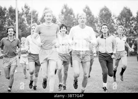Koedijk Brothers VV Beverwijk Football People and entraîneurs, Whizgle News, Dutch Desk, pays-Bas, 1950 - 2000 on 22-08-1986. Voici les rubriques de l'image. Un groupe de jeunes hommes est engagé dans une séance d'exercices animée, faisant du jogging énergique sur un terrain herbeux. La scène a une atmosphère dynamique et animée, remplie d'un sentiment de camaraderie et de mouvement. Au premier plan, plusieurs hommes mènent le peloton, présentant une variété de vêtements sportifs. Leurs shorts varient en longueur, certains optant pour des styles longueur genou tandis que d'autres arborent des coupes plus courtes. Les couleurs de leurs vêtements varient, avec quelques i Banque D'Images