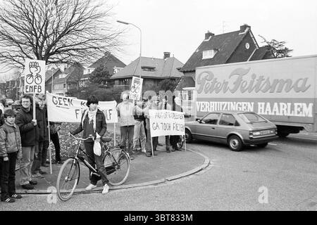 ENFB action pas de vague rouge pour les cyclistes Heemstede Heemsteedse Dreef pays-Bas, Whizgle News, Dutch Desk, pays-Bas, 1950 - 2000 on 03-1982. Ces rubriques apparaissent dans l'image. La scène capture une manifestation animée se déroulant dans une rue de banlieue. Au premier plan, une femme se tient confiante à côté d'un vélo vintage, vêtue d'une tenue décontractée, dégageant un sentiment de détermination. Elle fait face à la caméra, ancrant la scène avec une présence palpable. Autour d'elle, un groupe d'individus tient divers panneaux, certains élevés en hauteur, affichant des slogans qui plaident pour les droits du cyclisme ou expr Banque D'Images