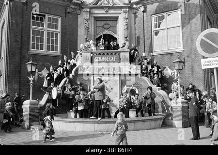 Carnival Parade Zandvoort Carnival, Whizgle News, Dutch Desk, pays-Bas, 1950 - 2000 le 28-02-1976. L'image montre ces rubriques. La scène est un rassemblement animé en plein air, centré autour d'un escalier orné menant à un grand bâtiment, présentant une façade complexe. L'architecture comporte des éléments décoratifs, peut-être des sculptures en pierre, et de multiples grandes fenêtres qui reflètent l'activité au sein de la structure. Dans les escaliers, un groupe diversifié d'individus occupe divers endroits. Certains se tiennent fièrement debout, tandis que d'autres sont assis ou appuyés contre les balustrades. La tenue vestimentaire varie, indiquant un festi Banque D'Images