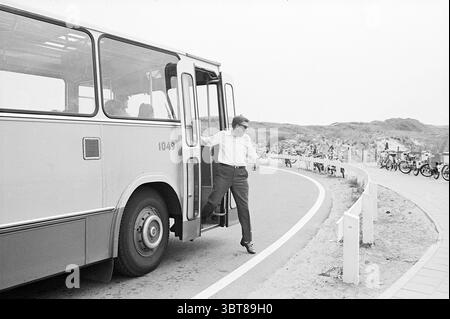 Bus sur Boulevard Noord Zuid Hollandse Vervoersmaatschappij N.V. NZ, Whizgle News, Dutch Desk, pays-Bas, 1950 - 2000 on 12-08-1969. L'image inclut ces rubriques. Dans un cadre paisible et extérieur, un bus est stationné le long d'une route légèrement courbe. Le bus, caractérisé par son design simple et un schéma de couleurs blanc et clair, a sa porte entrouverte, indiquant un arrêt récent. Un homme est en train de descendre du véhicule, vêtu d'une chemise blanche et nette et d'un pantalon sombre, suggérant une apparence décontractée mais polie. Sa posture est confiante, suggérant un sens du but. L'arrière-plan featu Banque D'Images