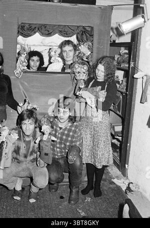 Théâtre de marionnettes Plop' Pencentrale IJmuiden' Puppets spectacles de marionnettes spectacles de marionnettes théâtre de marionnettes, Whizgle News, Dutch Desk, pays-Bas, 1950 - 2000 on 13-12-1975. L'image montre ces rubriques. La scène se déroule dans un espace confortable, quelque peu encombré, probablement un atelier ou un environnement de théâtre. La toile de fond se compose d'un rideau de couleur profonde, qui crée un sentiment d'intimité et de concentration. Une petite fenêtre dans le rideau révèle une poignée de visages qui regardent, contribuant à une atmosphère ludique et curieuse. Au premier plan, un groupe d'individus est rassemblé, chacun tenant diverses marionnettes, qui sont vibra Banque D'Images