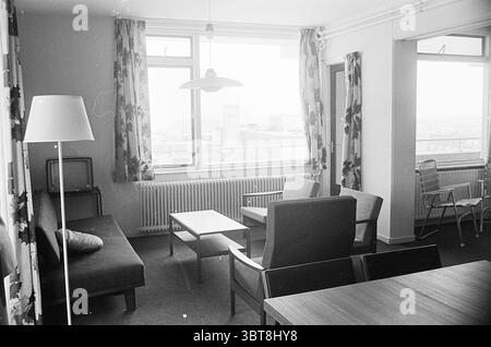 Badhotel Zandvoort Hotels, Whizgle News, Dutch Desk, pays-Bas, 1950 - 2000 on 03-07-1963. Ces rubriques sont illustrées dans l'image. La scène présente un salon peu meublé avec une esthétique épurée et minimaliste. Au centre, il y a une table basse rectangulaire en bois clair, positionnée entre un canapé gris accueillant et une paire de fauteuils. Le canapé a un design moderne et discret, tandis que les fauteuils présentent une silhouette plus classique avec un rembourrage sombre. De grandes fenêtres sur un mur permettent à la lumière naturelle de filtrer, créant un environnement légèrement éclairé. Le rideau Banque D'Images